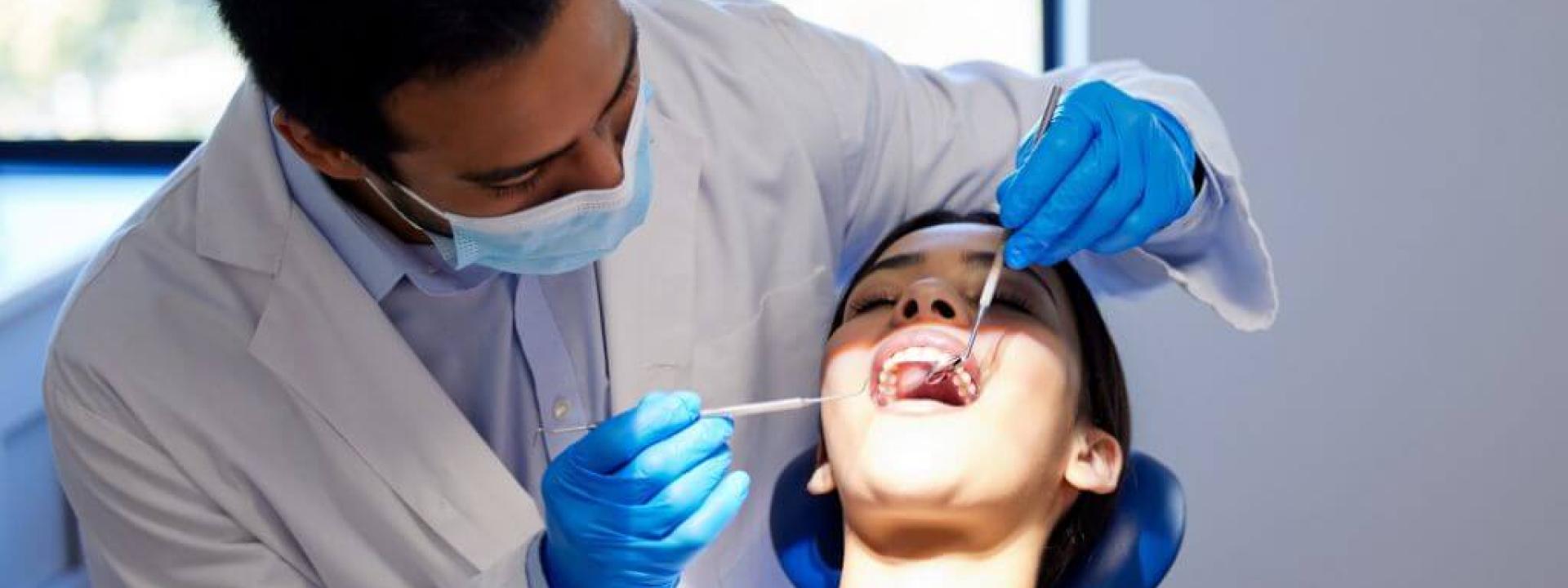 Male dentist performing dental work on female patient 